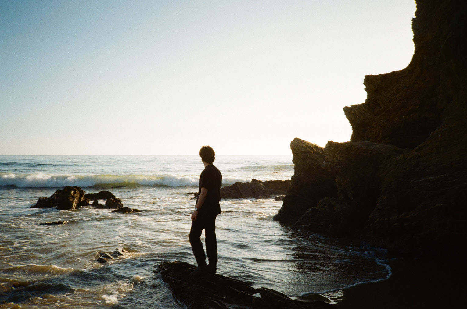 Me standing on a rock outcropping looking at the ocean as the tide comes in